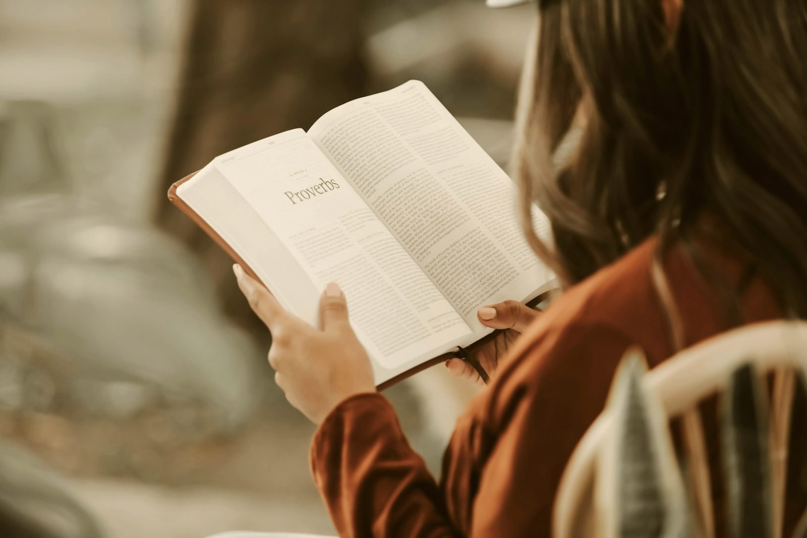 A reader holding an open book, seen over the shoulder