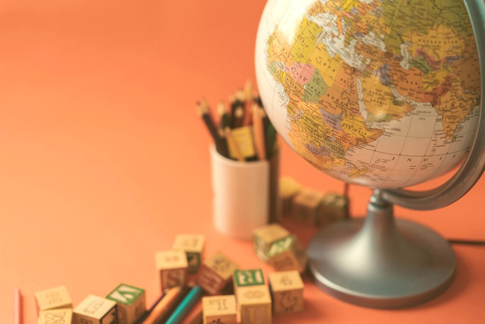 A desk globe beside a pot of pencils and wooden alphabet blocks