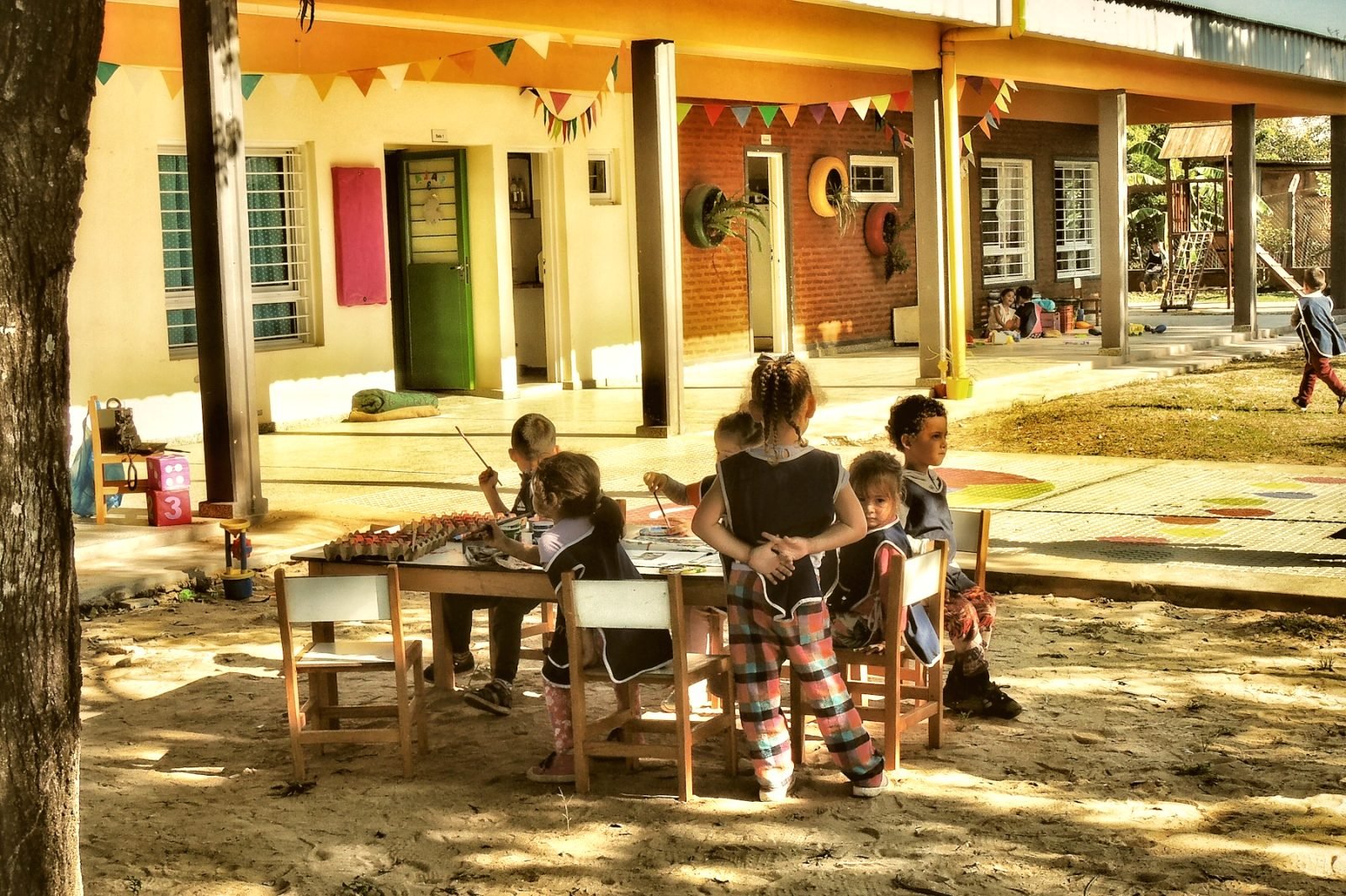 Young children working together at a low table in an open-air classroom