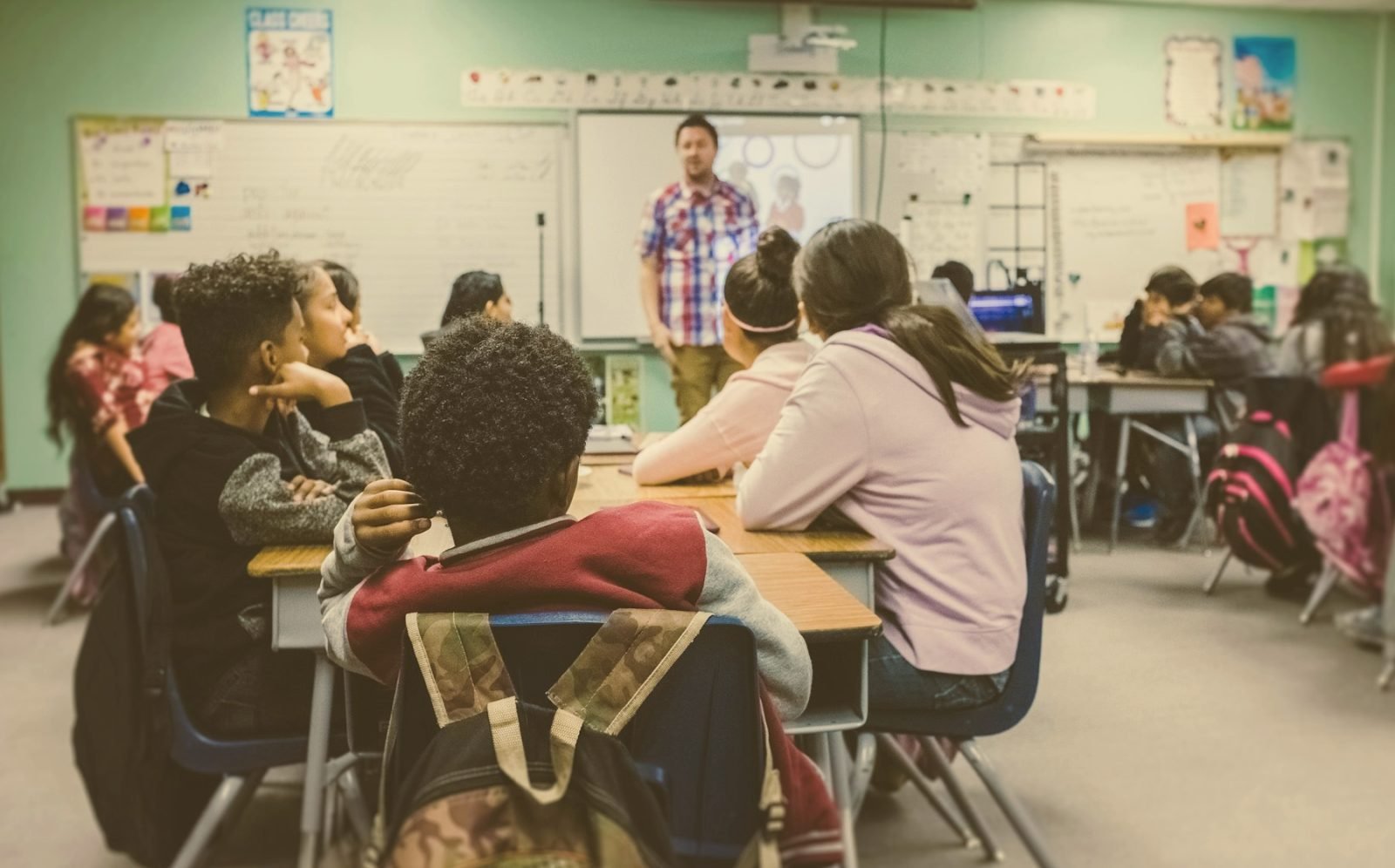 A teacher at the front of a classroom of attentive children
